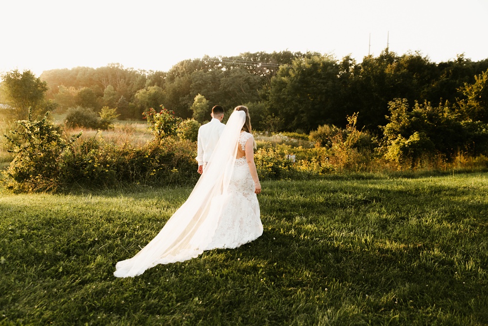 bride and groom holding hands in field at metea county park fall wedding