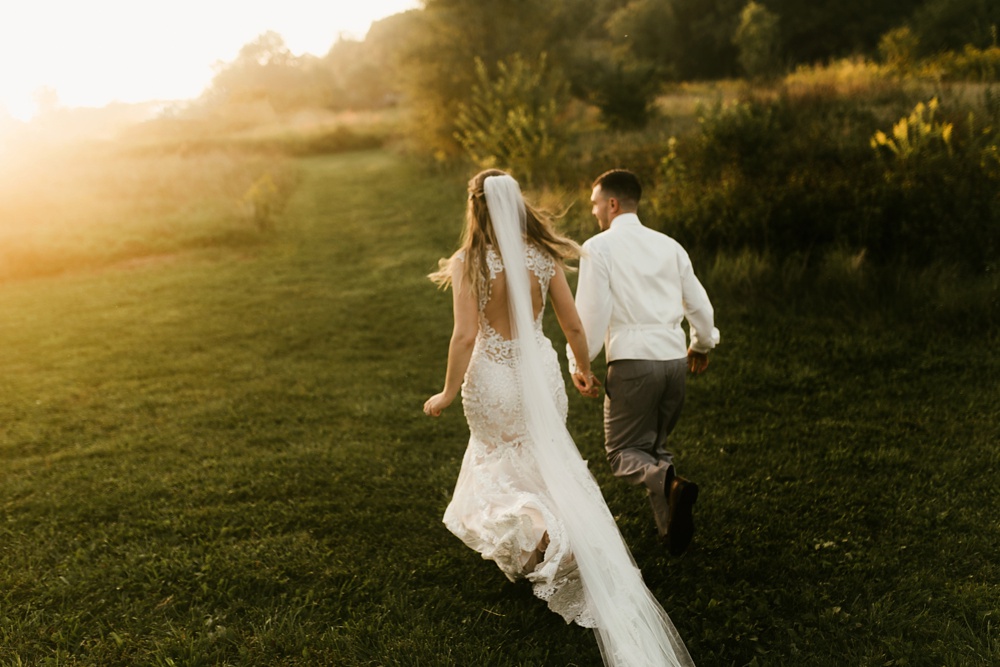 bride and groom running through field at sunset at metea county park fall wedding