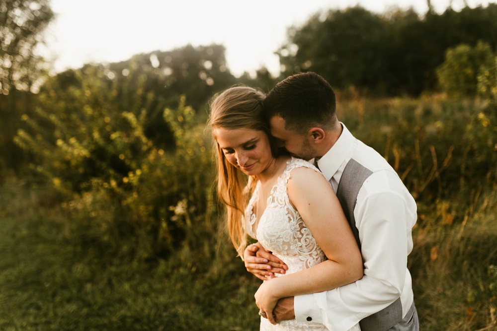 bride and groom hugging in field at sunset at metea county park fall wedding