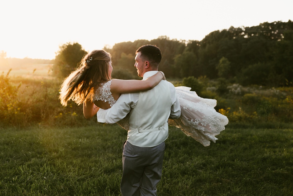 groom carrying bride at sunset at metea county park fall wedding