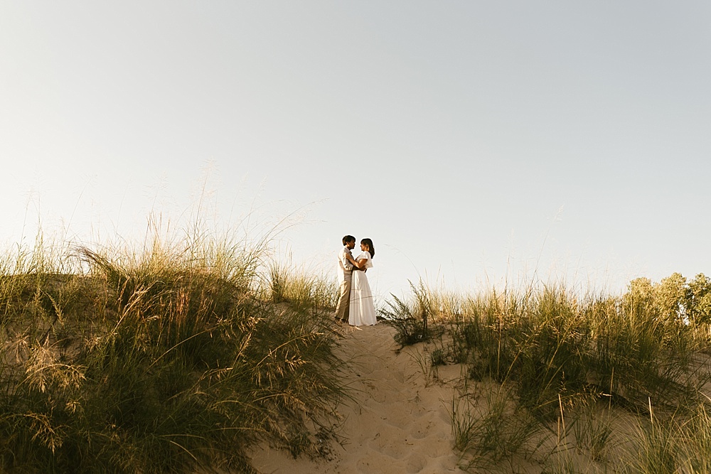 couple standing on top of sand dune at warren dunes van life engagement shoot