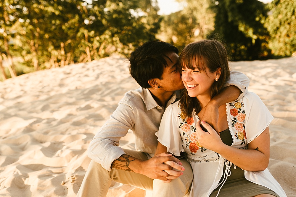 man kissing fiances cheek at warren dunes van life engagement shoot