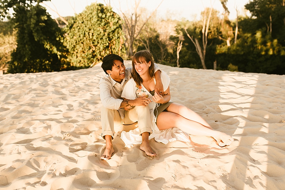 couple hugging on sand at warren dunes van life engagement shoot