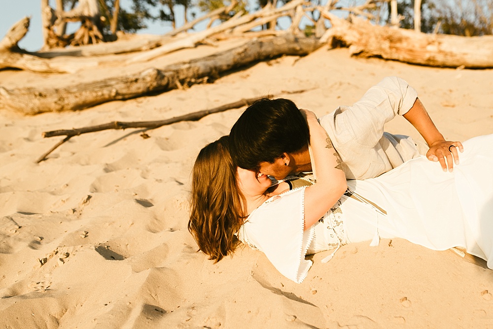 couple kissing in sand at warren dunes van life engagement shoot