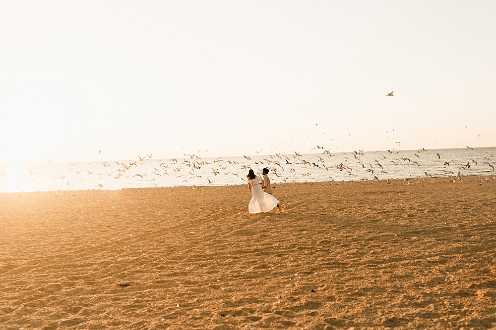 couple running down beacch at warren dunes van life engagement shoot