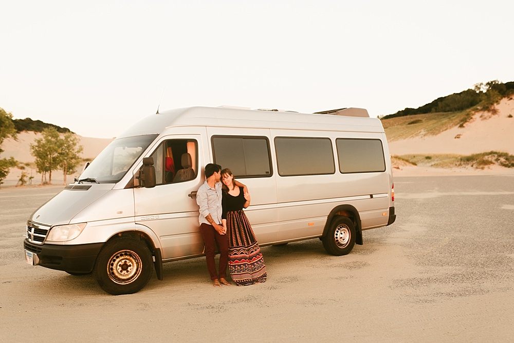 couple leaning against their converted home van at warren dunes van life engagement shoot