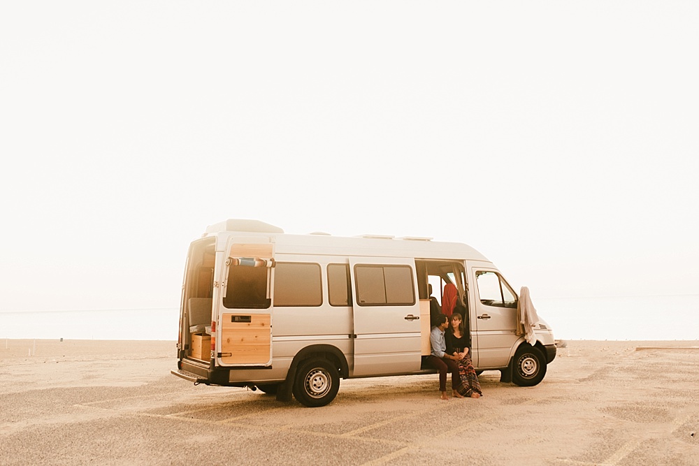 couple sitting in their converted home van at warren dunes van life engagement shoot