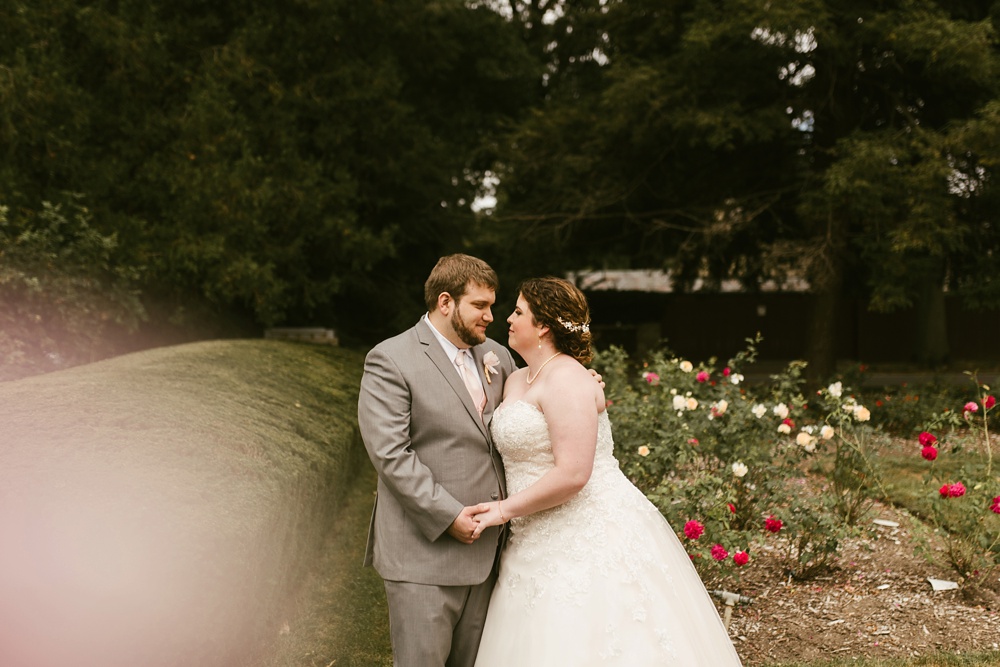 couple smiling among flowers at foster park wedding photos