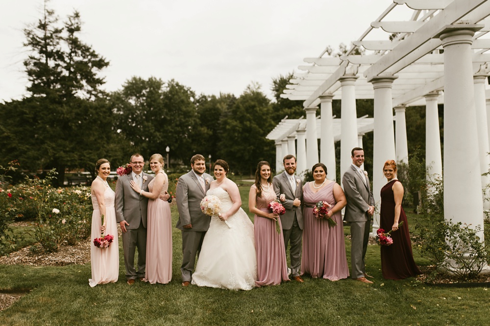 wedding party in blush dresses and gray tuxes posing with couple at foster park wedding