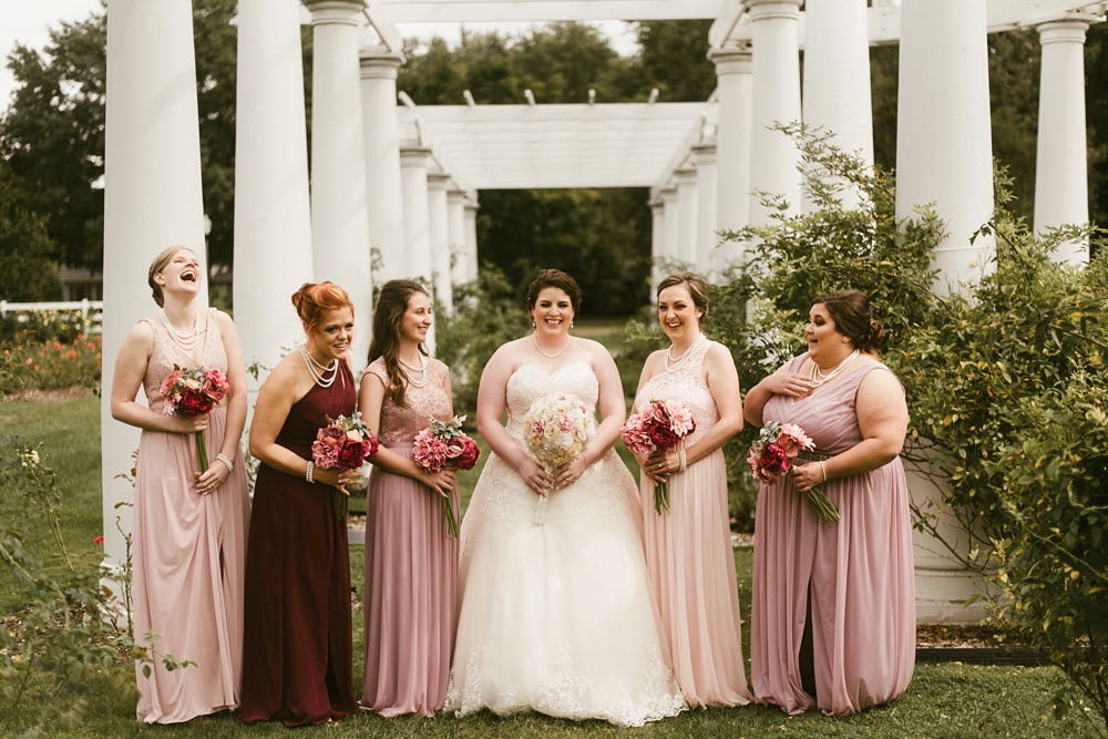 bridesmaids in blush dresses smiling at bride at foster park wedding