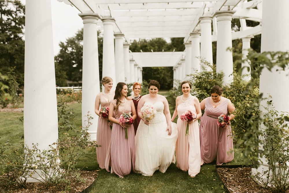 bridesmaids in blush dresses walking with bride at foster park wedding