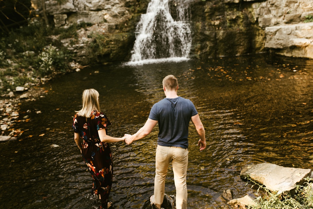 couple walking into waterfall at france park engagement session