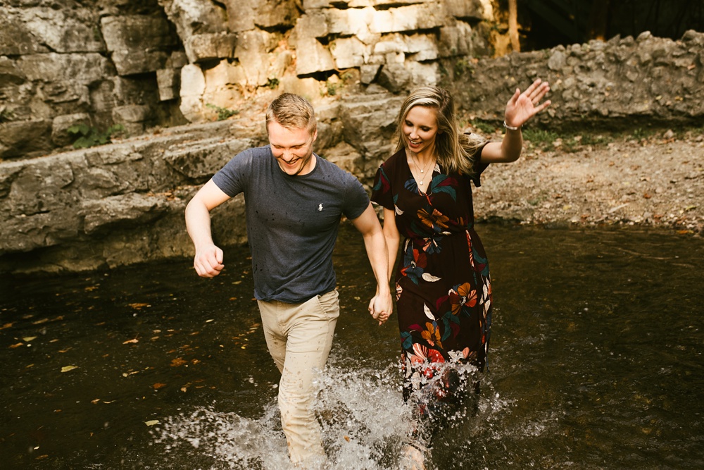 couple splashing in water at france park engagement session
