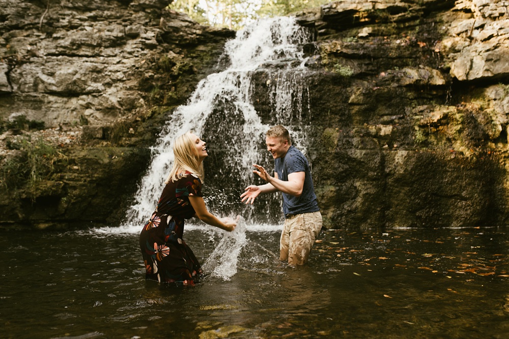 couple playing by waterfall at france park engagement session