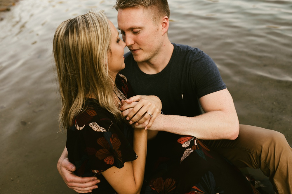 couple holding hands sitting in water at france park engagement session