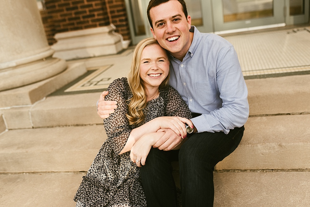 couple smiling on steps at downtown south bend engagement session
