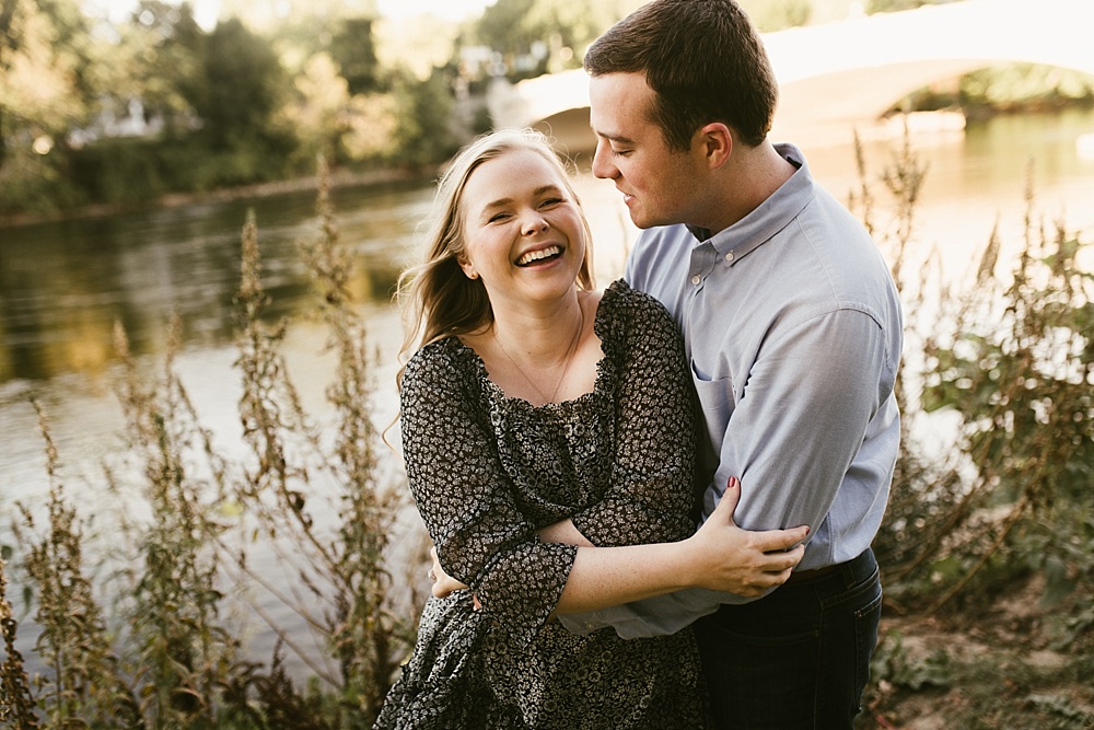 couple laughing by pond at downtown south bend engagement session