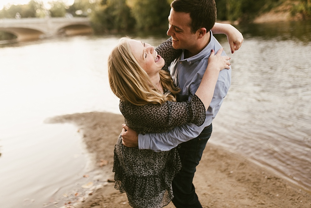 couple hugging by water at downtown south bend engagement session