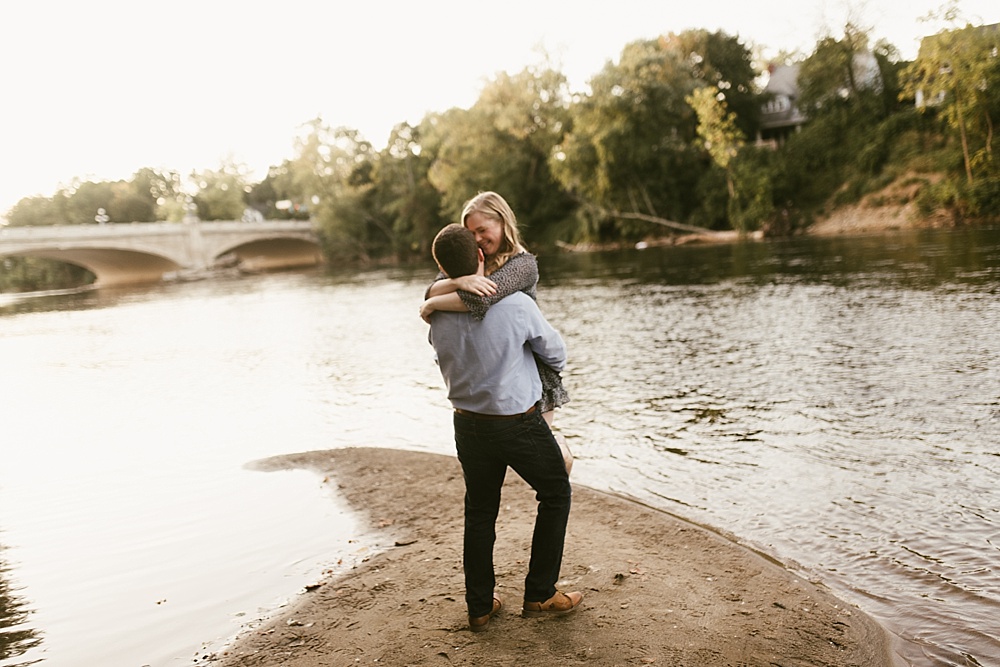 man picking up fiance by water at downtown south bend engagement session