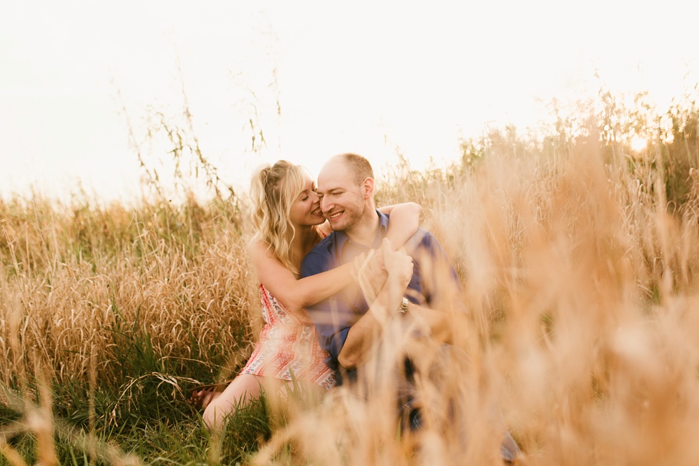 couple sitting by field at eagle marsh nature preserve engagement session