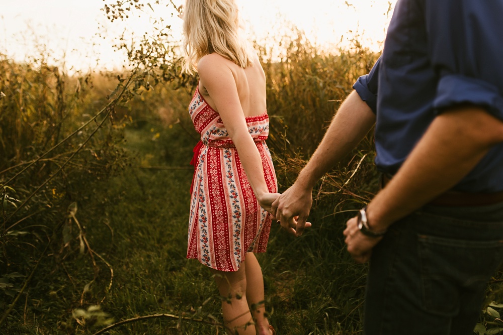 couple holding hands in field at eagle marsh nature preserve engagement session