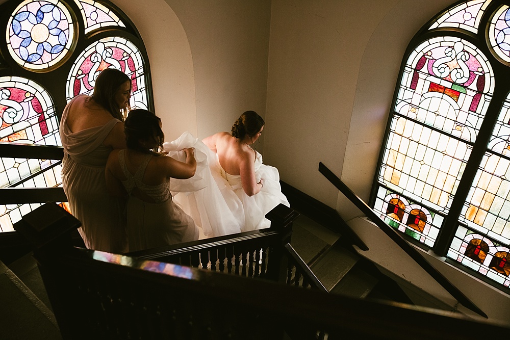 bride walking down stairs with stain glass at precious blood catholic church wedding