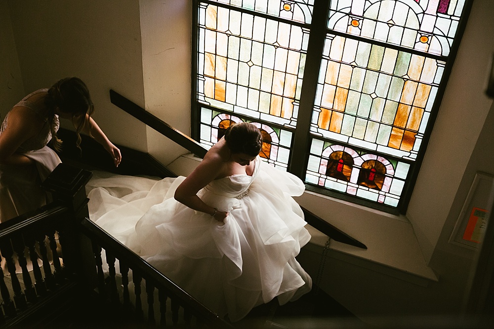 bride walking by stain glass window at precious blood catholic church wedding