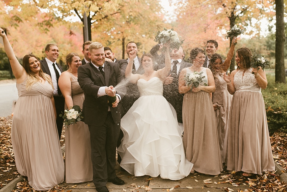 wedding party popping champagne at headwaters park fall wedding