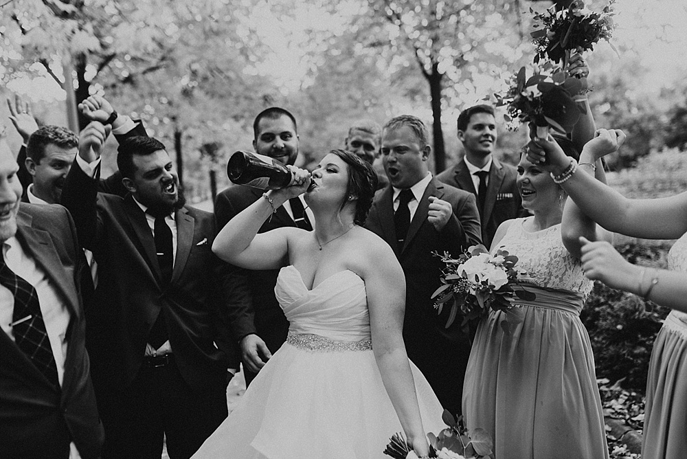 bride drinking champagne from the bottle at headwaters park fall wedding