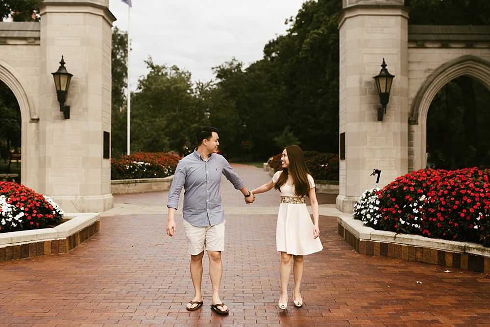 couple holding hands by iu sample gates at indiana university bloomington engagement session