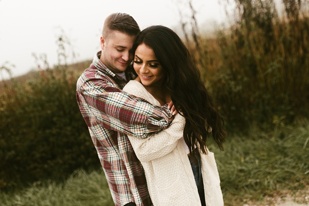 couple hugging next to field at sunrise eagle marsh engagement session