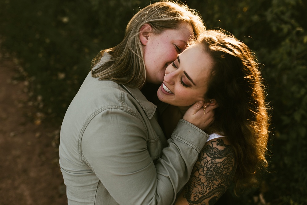 couple smiling and kissing at coffee creek watershed preserve engagement session