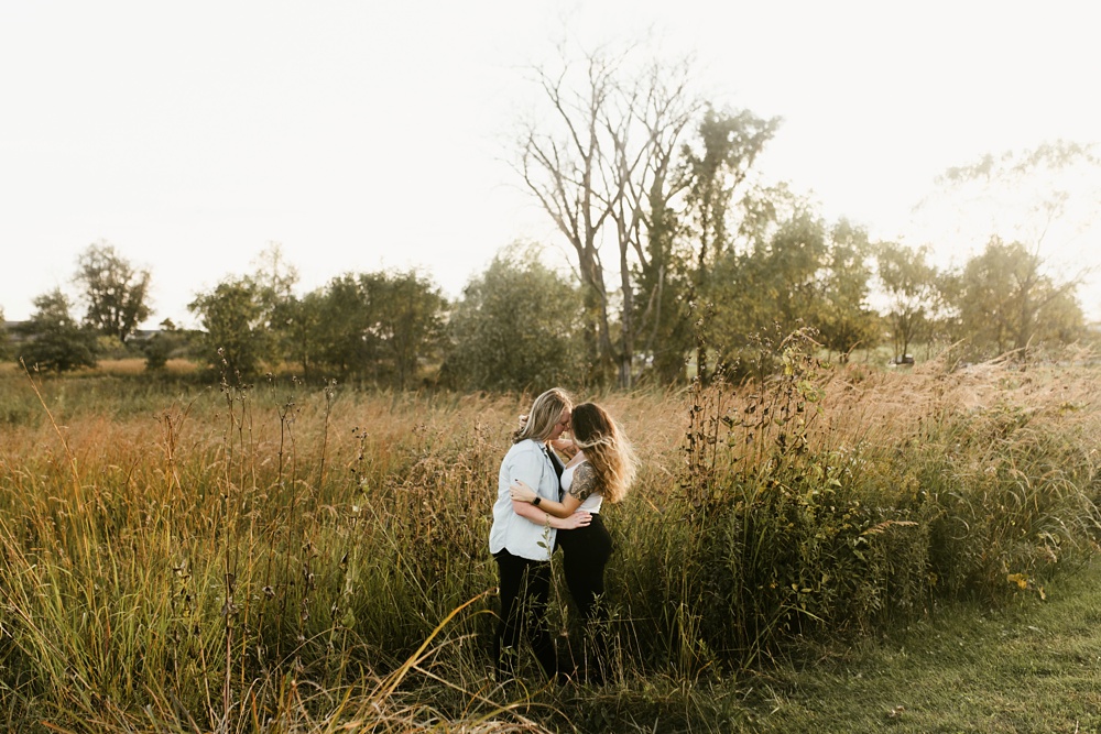 couple kissing in field at sunset at coffee creek watershed preserve engagement session