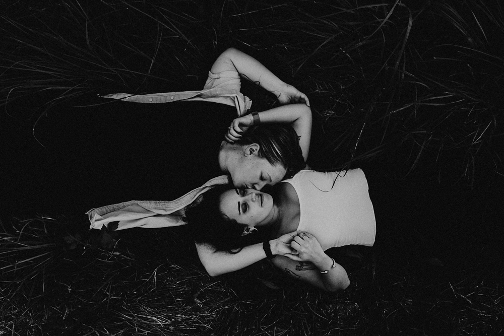 couple laying in grass at coffee creek watershed preserve engagement session