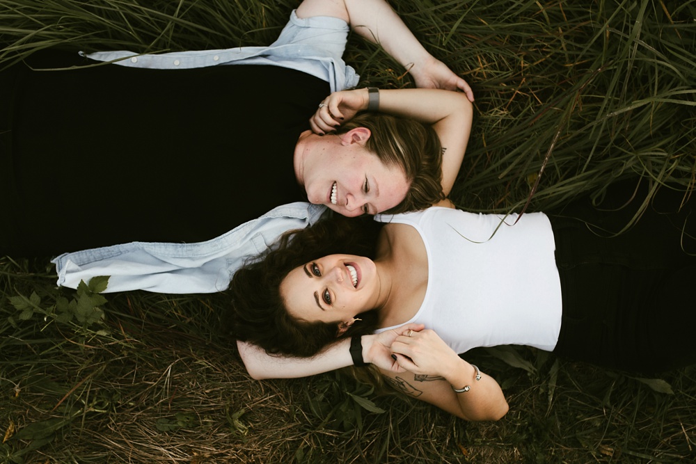 couple laughing on grass at coffee creek watershed preserve engagement session
