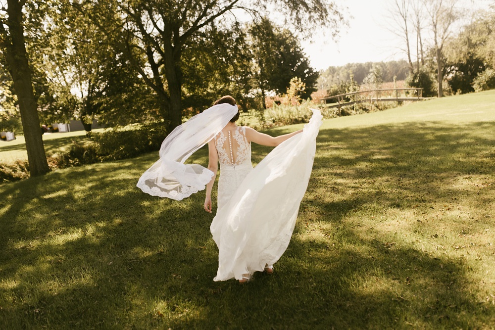 bride walking with flowing skirt in marie gabrielle couture dreess at indiana wesleyan fairmount campground wedding