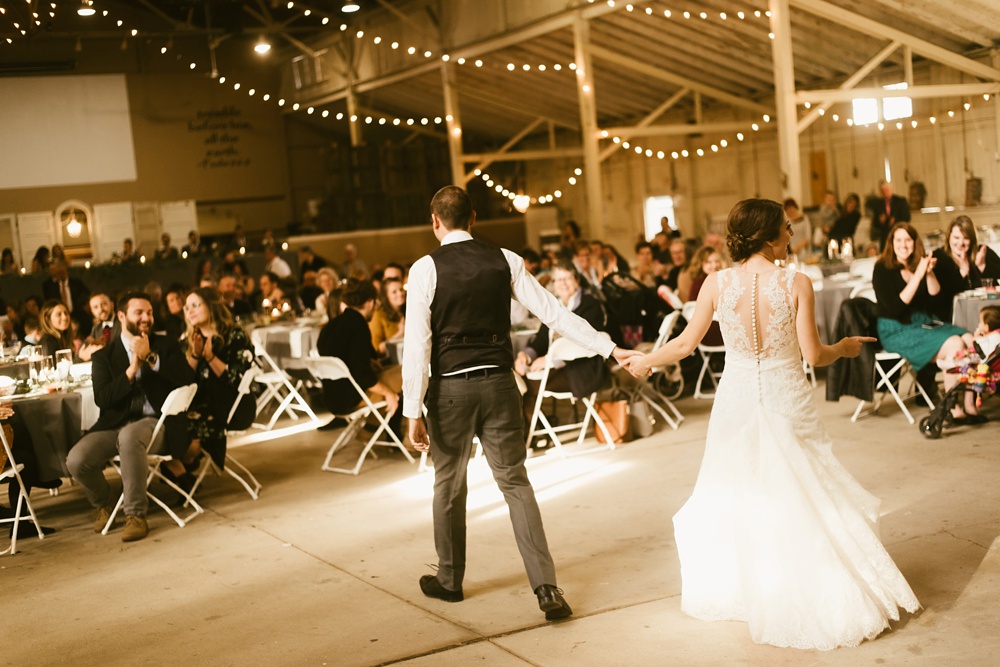 couple holding hands during first dance at indiana wesleyan fairmount campground wedding