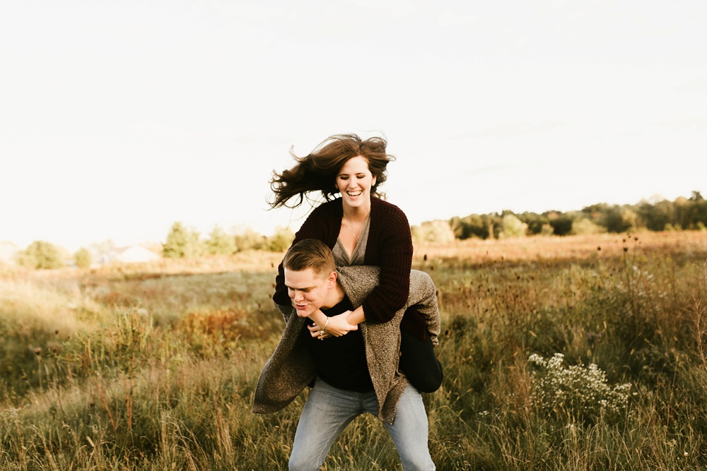 couple piggybacking in field at golden hour fort wayne autumn engagement session