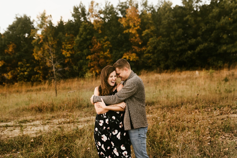 couple hugging by forest in field at golden hour fort wayne autumn engagement session
