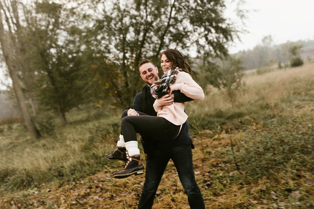 man carrying fiance in field in field at auburn sunrise engagement session