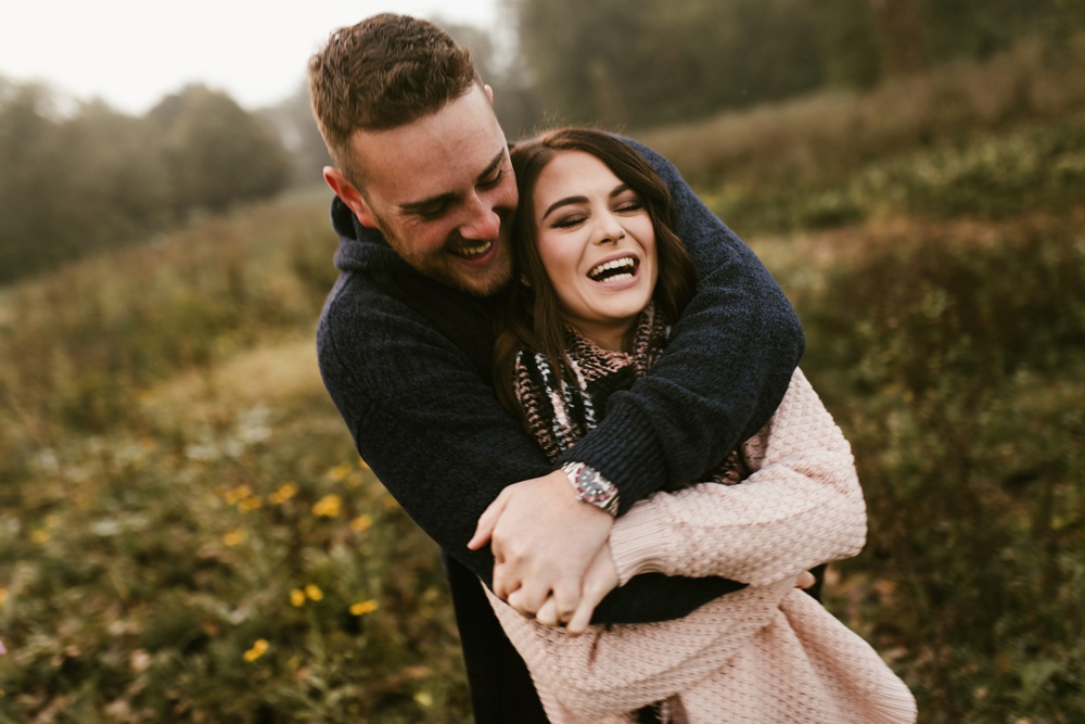 couple laughing in field at auburn sunrise engagement session