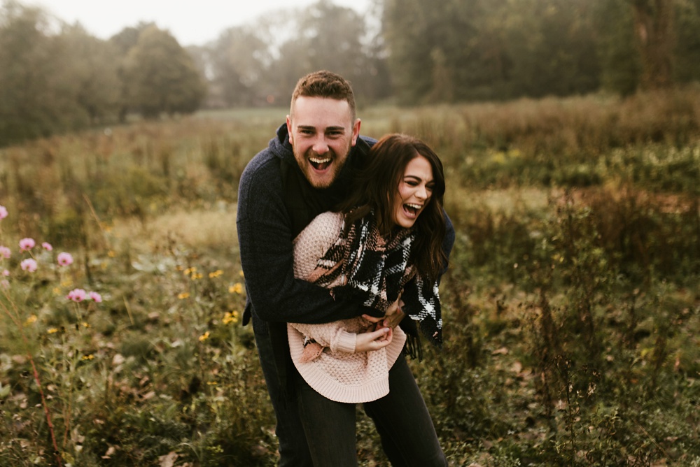 couple wrestling and laughing in field at auburn sunrise engagement session