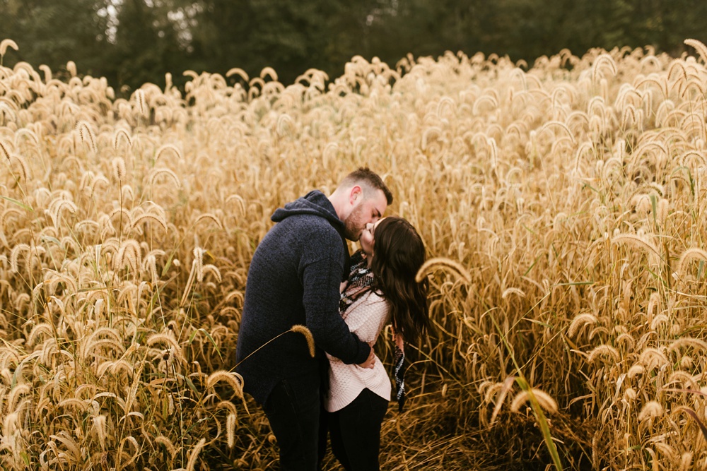 couple kissing in field at auburn sunrise engagement session