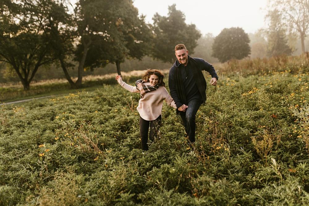 couple holding hands in field at auburn sunrise engagement session