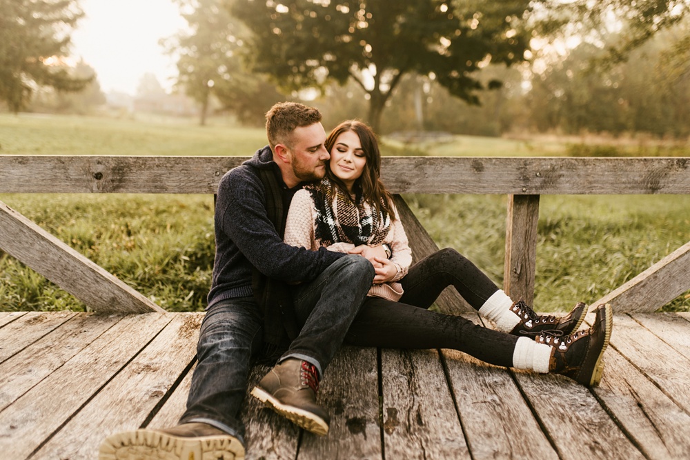 couple smiling on bridge in field at auburn sunrise engagement session