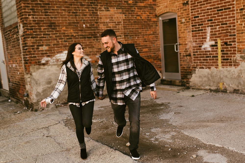 couple holding hands next to brick building at auburn sunrise engagement session