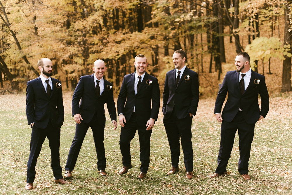groomsmen smiling in black tuxes at green bay pamperin park rock garden wedding