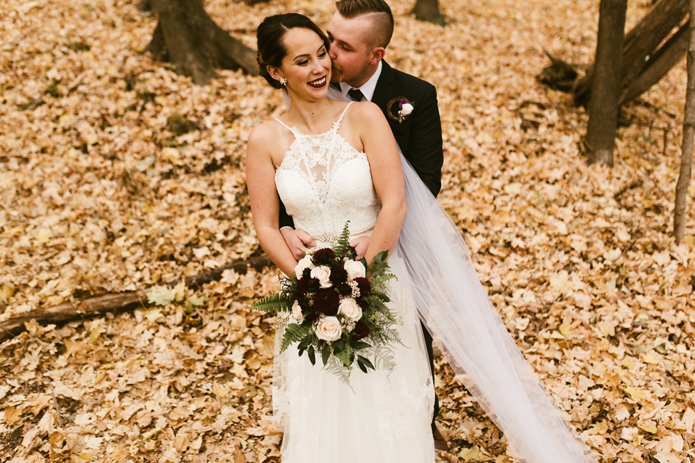 bride and groom kissing on fall leaves at green bay pamperin park rock garden wedding