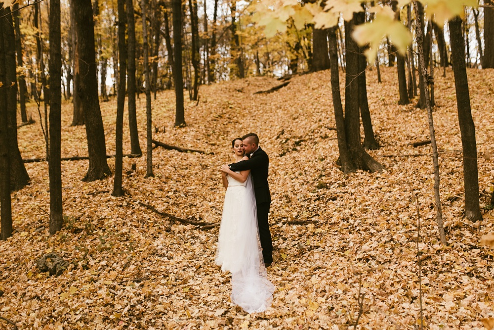 bride and groom hugging in fall leaves at green bay pamperin park rock garden wedding
