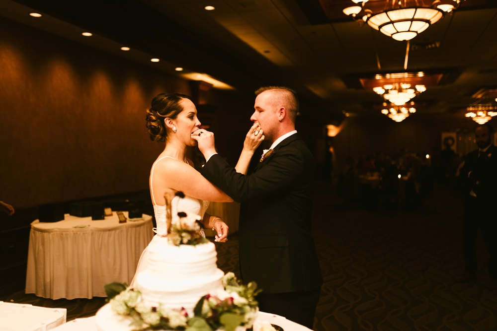 bride and groom eating cake at green baby pamperin park rock garden fall wedding